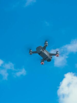 From below of bottom part of quadcopter with propellers and camera for taking photo and video in blue sky with clouds