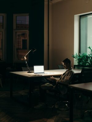 Man in Black and White Plaid Dress Shirt Sitting on Chair in Front of Macbook